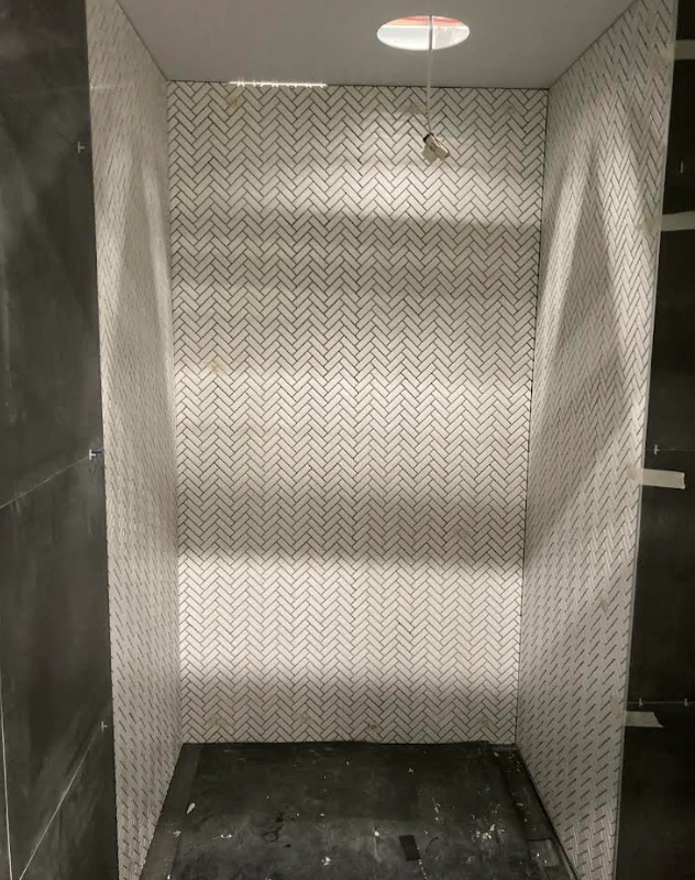 Shower recess tiled floor to ceiling in white herringbone mosaic